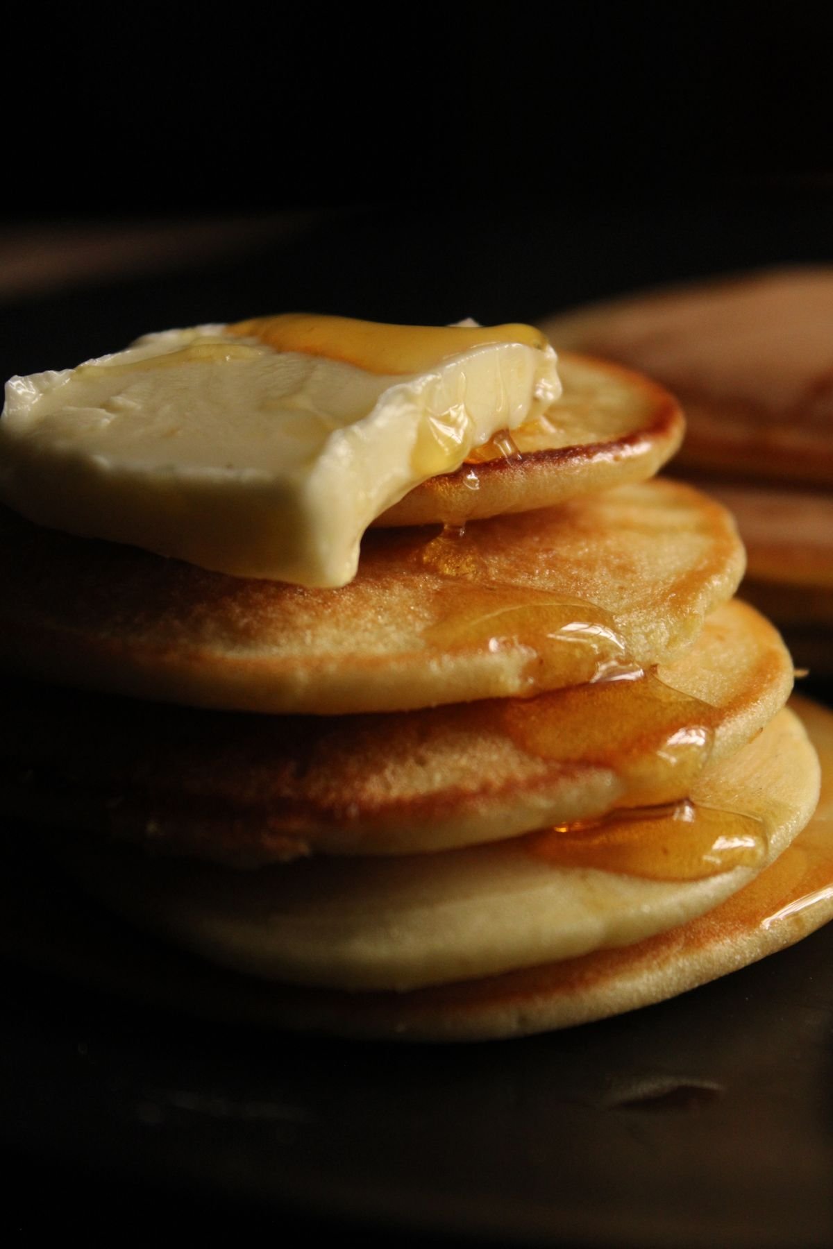 A stack of pancakes with a slab of butter melting and syrup running down