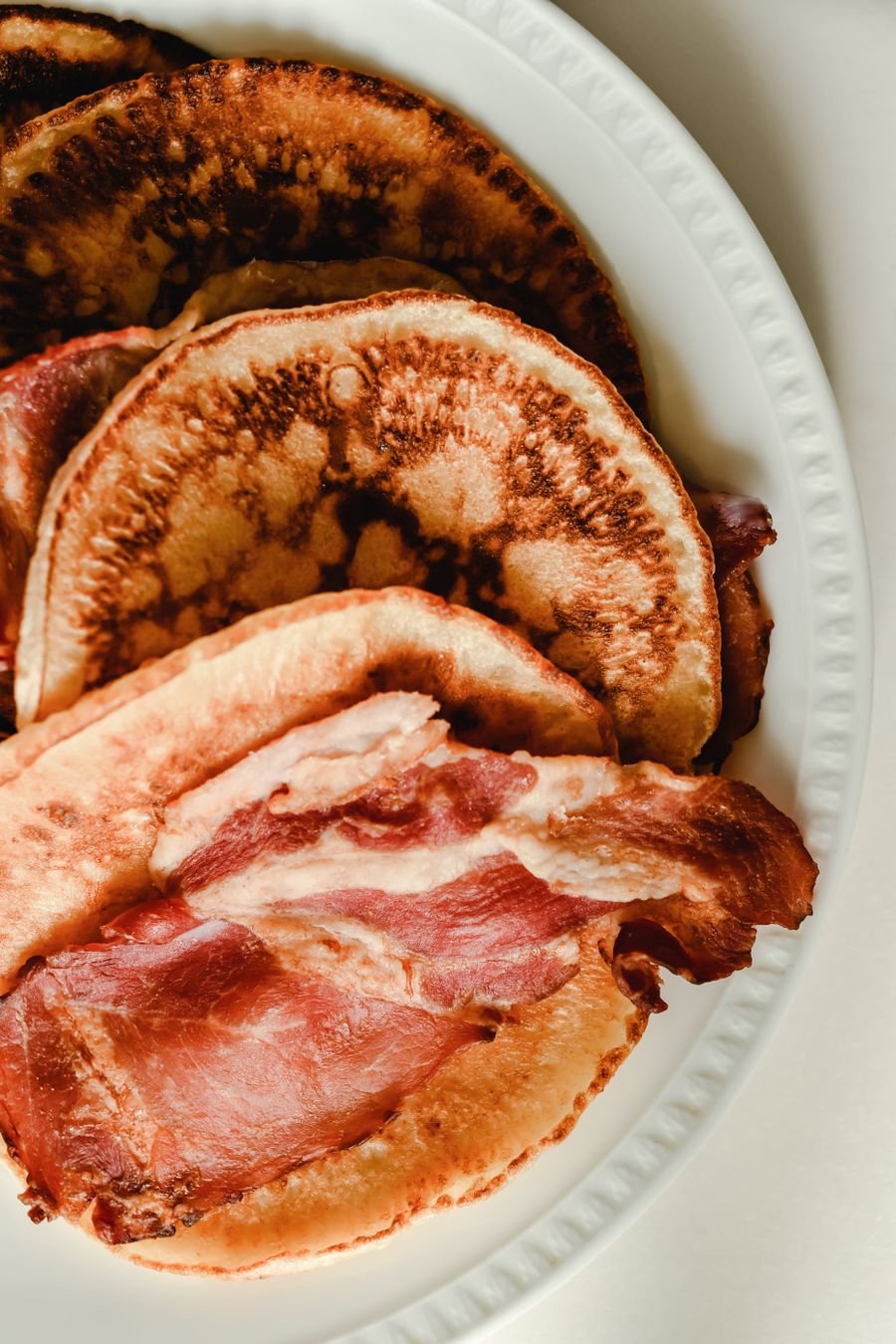 Pancakes served with crisp bacon on a white plate